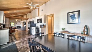 A spacious kitchen with wooden beams, a dining area with a long table and benches, and a framed artwork on the wall. - Waterfront Onamia Retreat w/ Dock & Fire Pit! (Onamia)