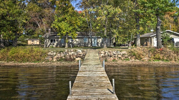 A wooden dock leading to a house by a calm body of water, surrounded by trees and a stone wall. - Waterfront Onamia Retreat w/ Dock & Fire Pit! (Onamia)