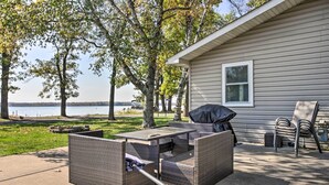 An outdoor patio with wicker furniture, a grill, and a view of a lake. - Waterfront Onamia Retreat w/ Dock & Fire Pit! (Onamia)