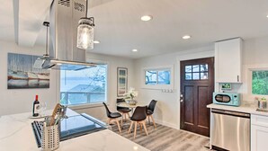 A modern kitchen with a marble countertop, a central island, and a dining area with a table and chairs. - Tacoma 'dash Point Beach Cabin' w/ Balcony! (Tacoma)