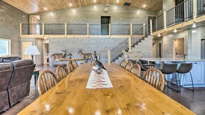 A spacious dining area with a long wooden table, surrounded by chairs, and a central decorative piece.
