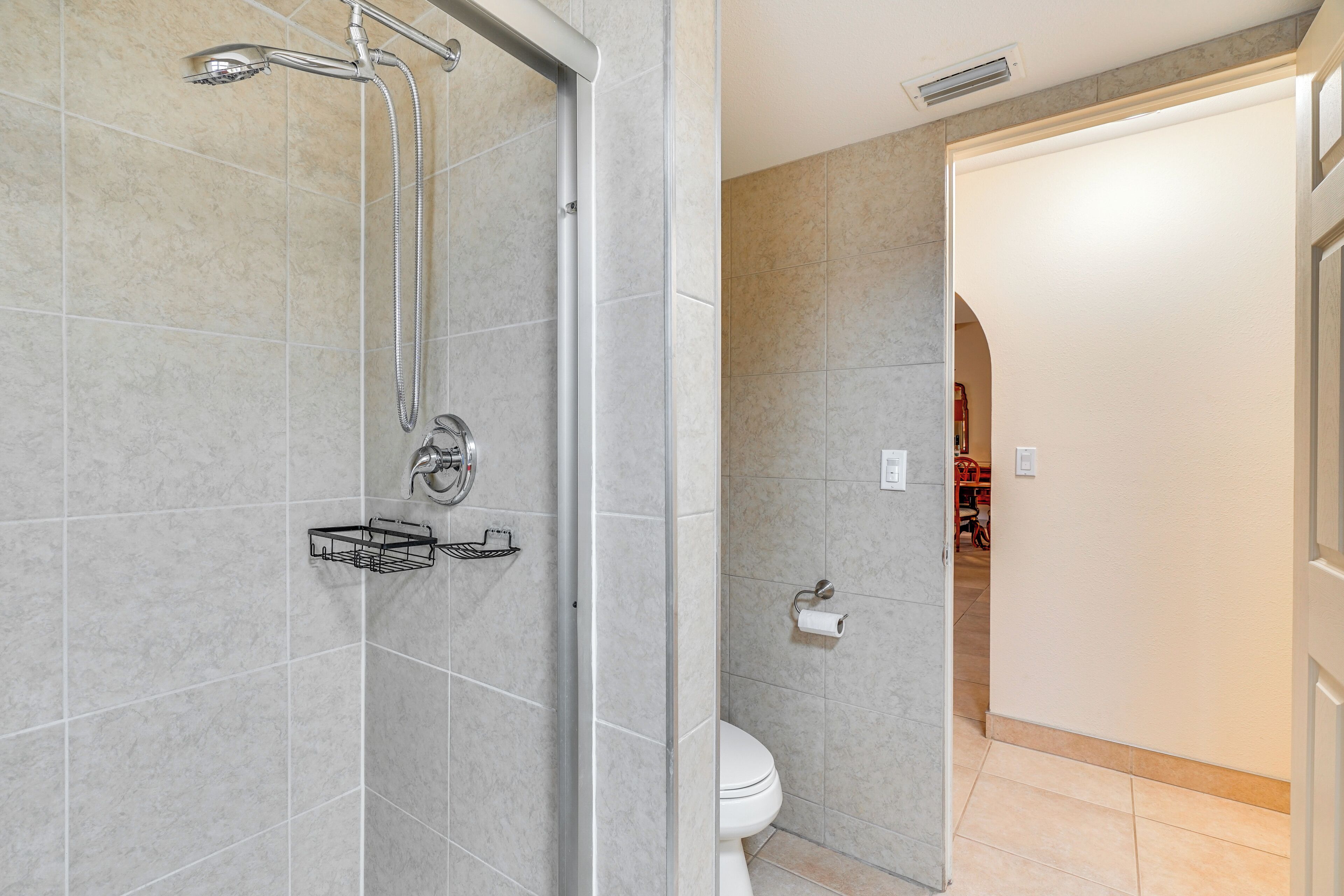 Baño con ducha, inodoro y perchero para toallas.
