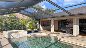 Une piscine avec un patio couvert, un jacuzzi et un espace salon extérieur.