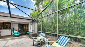 Un espace extérieur aménagé, abrité et doté de chaises et de tables, offrant une vue sur un jardin tropical.