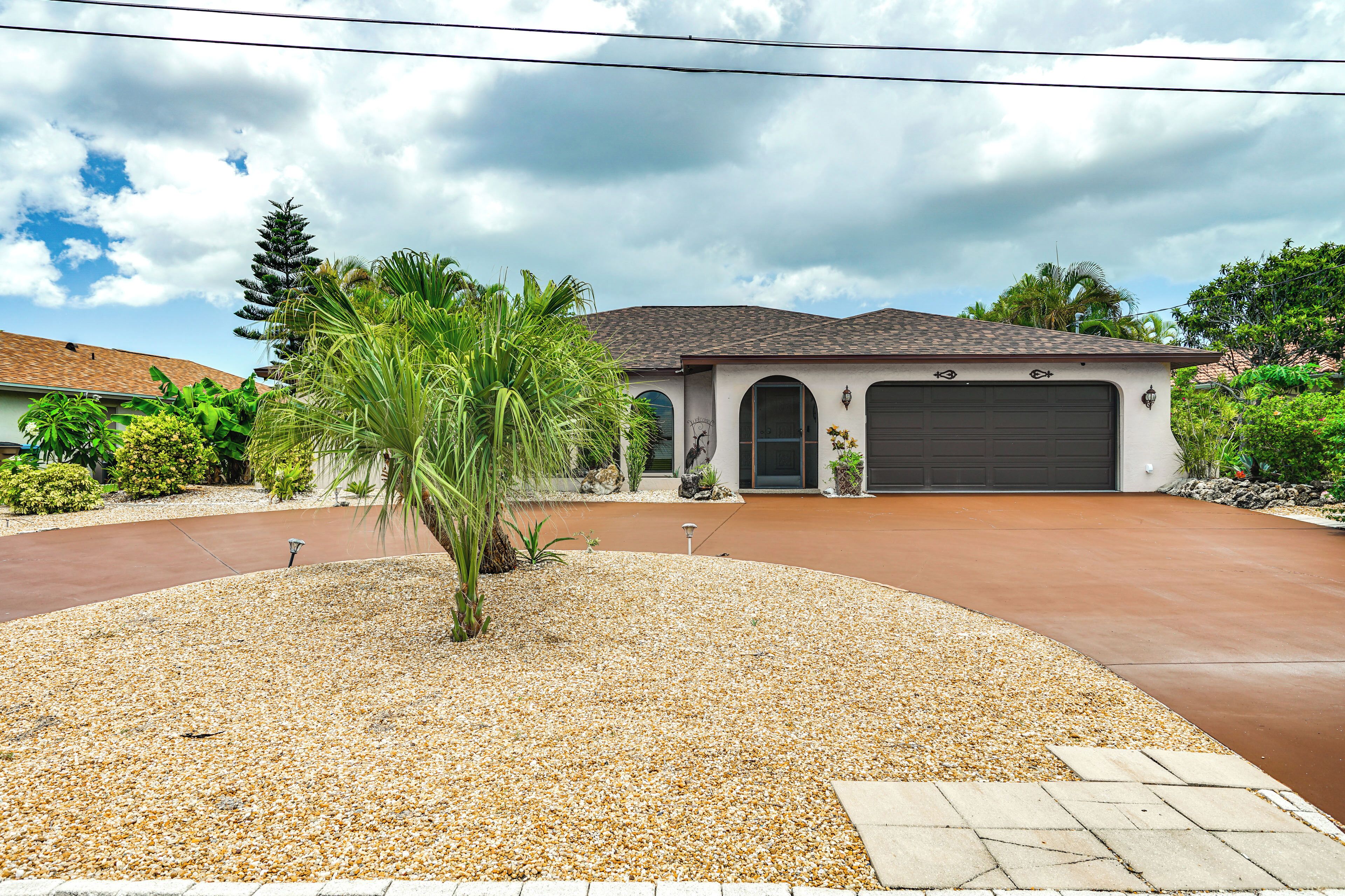 A residential house with a driveway, palm trees, and a garage.