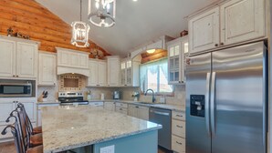 A kitchen with white cabinets, a stainless steel refrigerator, granite countertops, and a wooden ceiling. - 'the Cliffrose Cabin' - Hike, Relax, Explore! (Kanab)