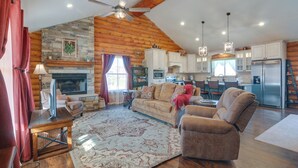 A spacious living area with a fireplace, a stone accent wall, and a kitchen with modern appliances. - 'the Cliffrose Cabin' - Hike, Relax, Explore! (Kanab)