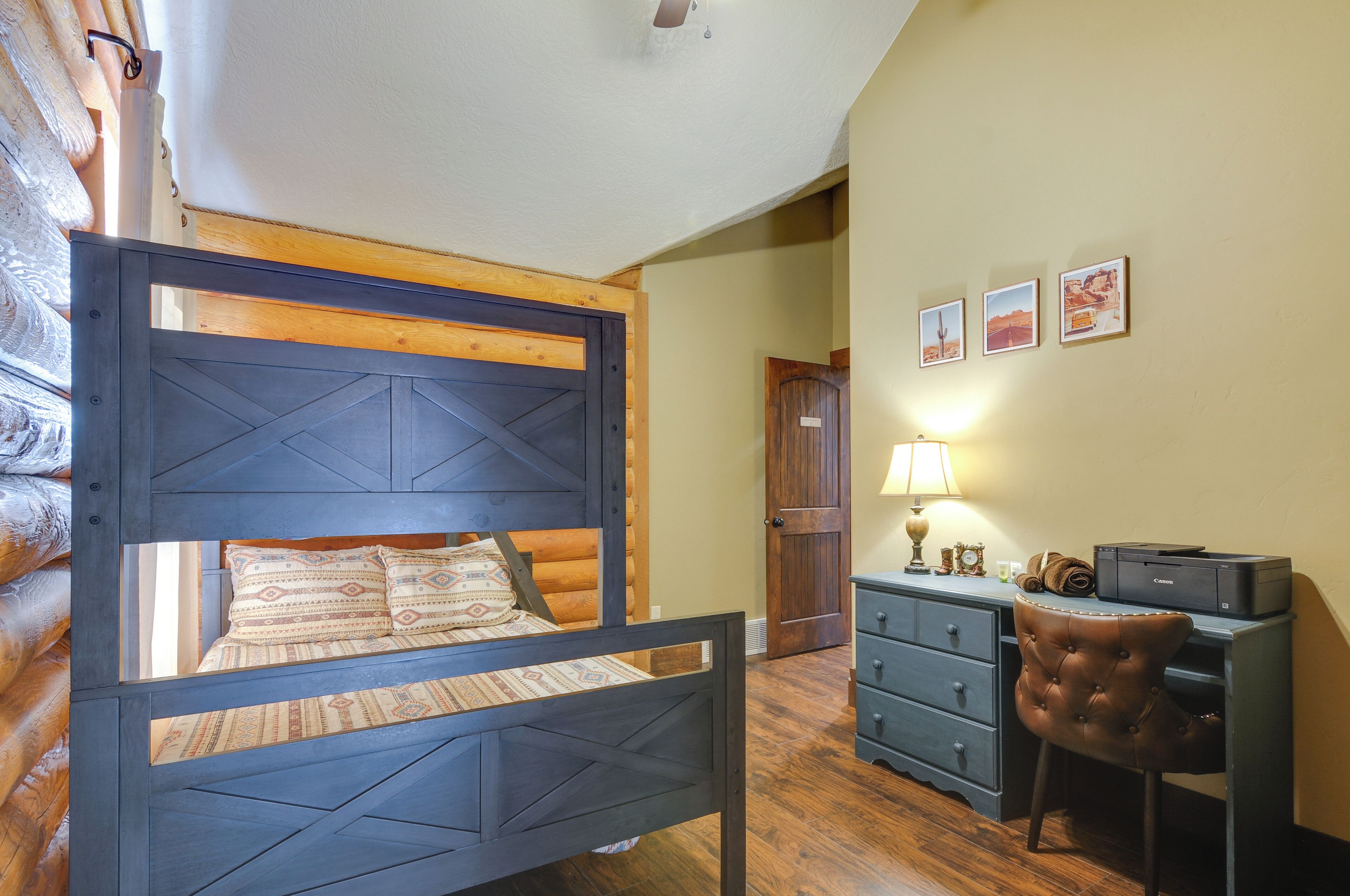 A room with a bed, desk, chair, and a door leading to another room.