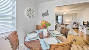 A dining area with a round table set for four, a clock, and a wall-mounted sign. - Longview Vacation Rental Home: 4 Mi to Dtwn (Longview)