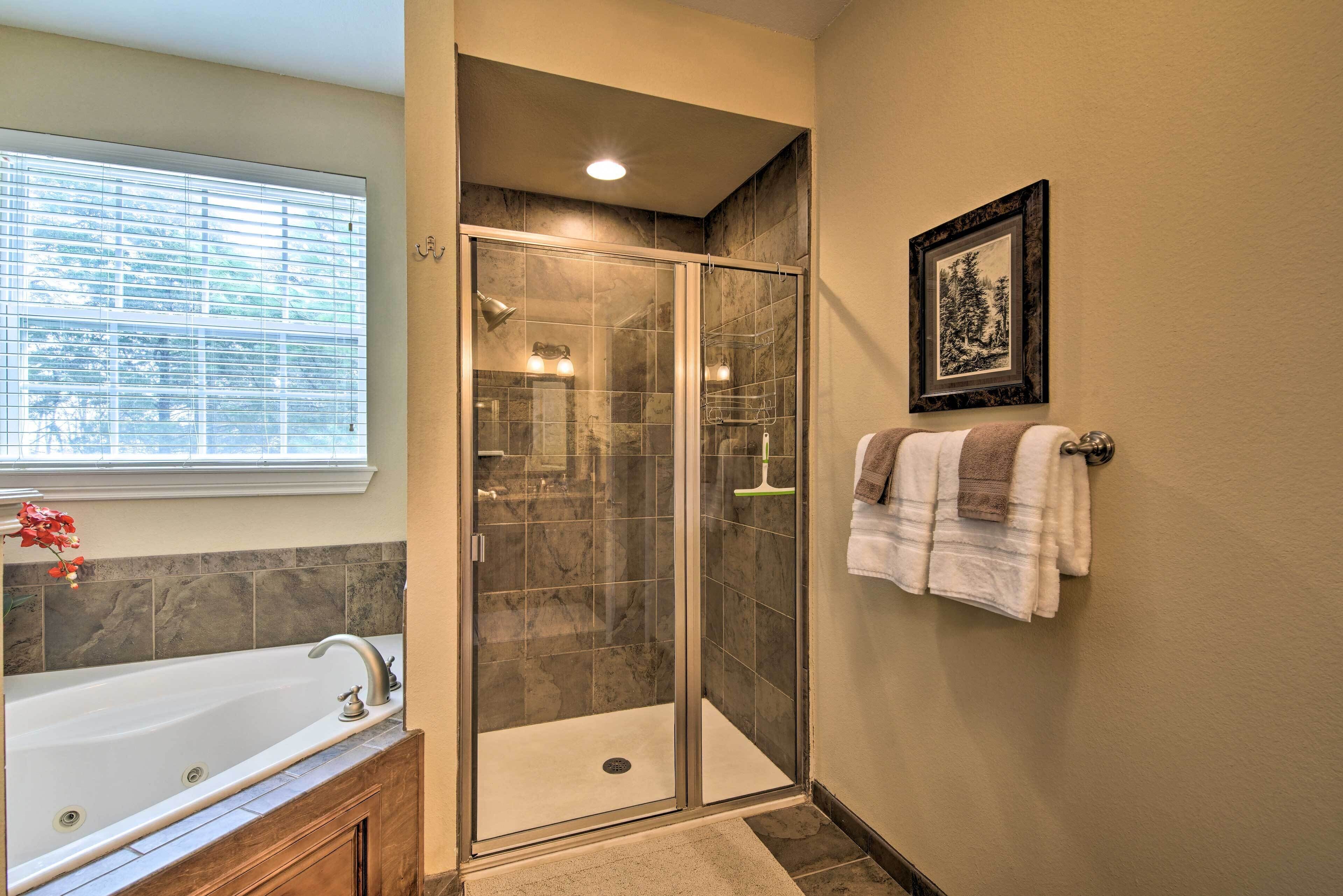 A bathroom with a glass-enclosed shower, a bathtub, and a towel rack with towels.