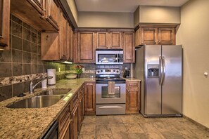 A kitchen with granite countertops, stainless steel appliances, wooden cabinets, and a tiled backsplash. - Cozy Holiday Getaway: Branson Condo 3 Mi to Dtwn! (Branson)