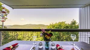 A table set for two with a view of green hills and a clear sky. - Breathtaking Highlands Condo w/ Mountain View (Highlands)