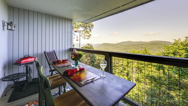 A balcony with a table set for two, a grill, and a view of a mountainous landscape. - Breathtaking Highlands Condo w/ Mountain View (Highlands)