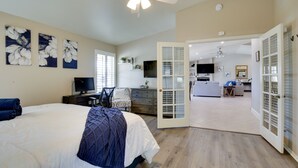 Una camera da letto con un letto, una scrivania e una TV. Si apre una porta su una zona living con un divano e un tavolo da pranzo.