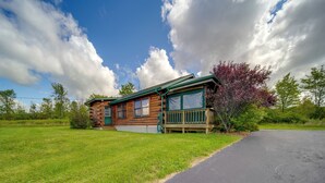 Una baita di legno con un portico verde e un vialetto lastricato.