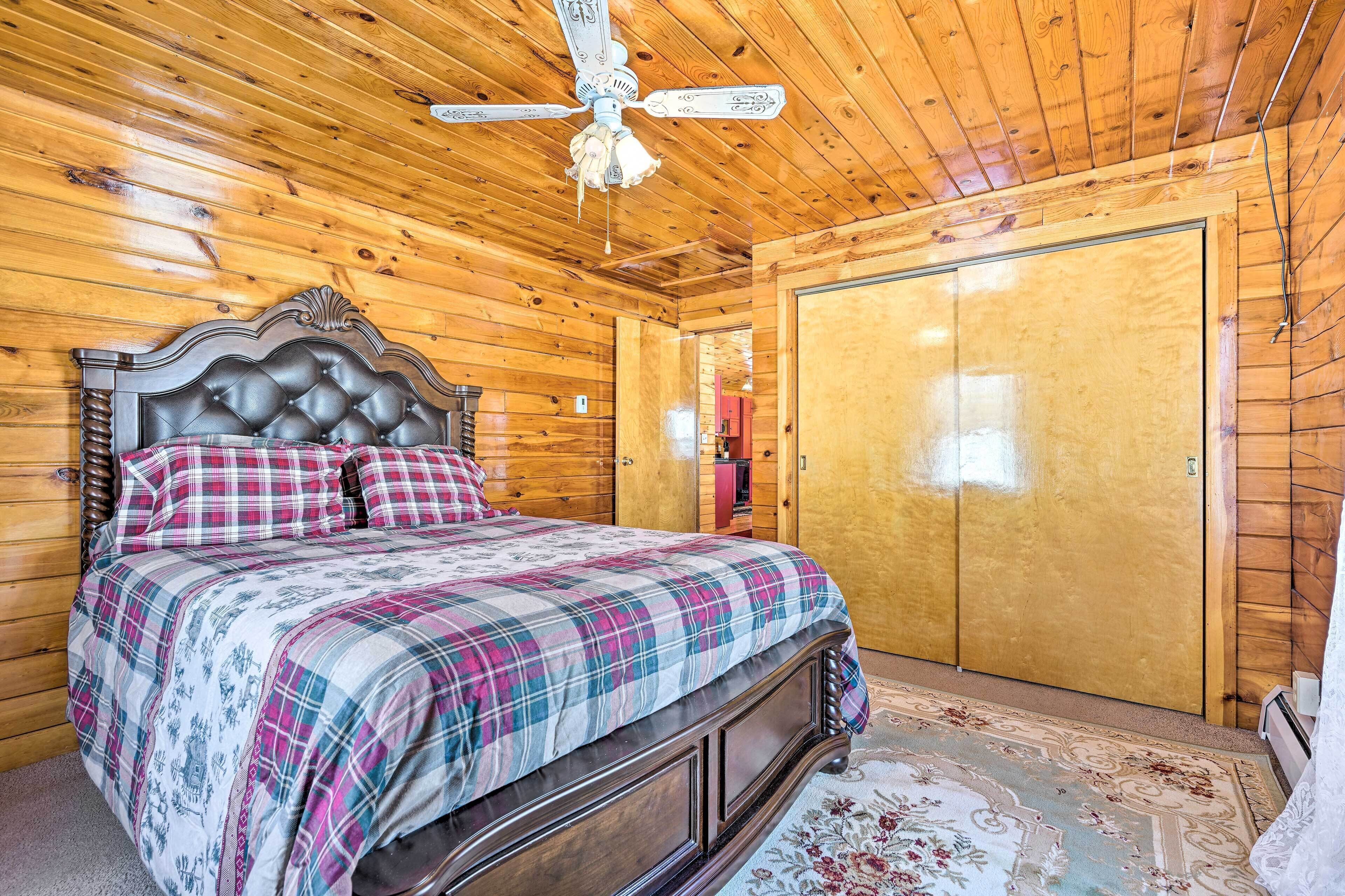 A wooden-paneled bedroom with a bed, a ceiling fan, and a wardrobe.