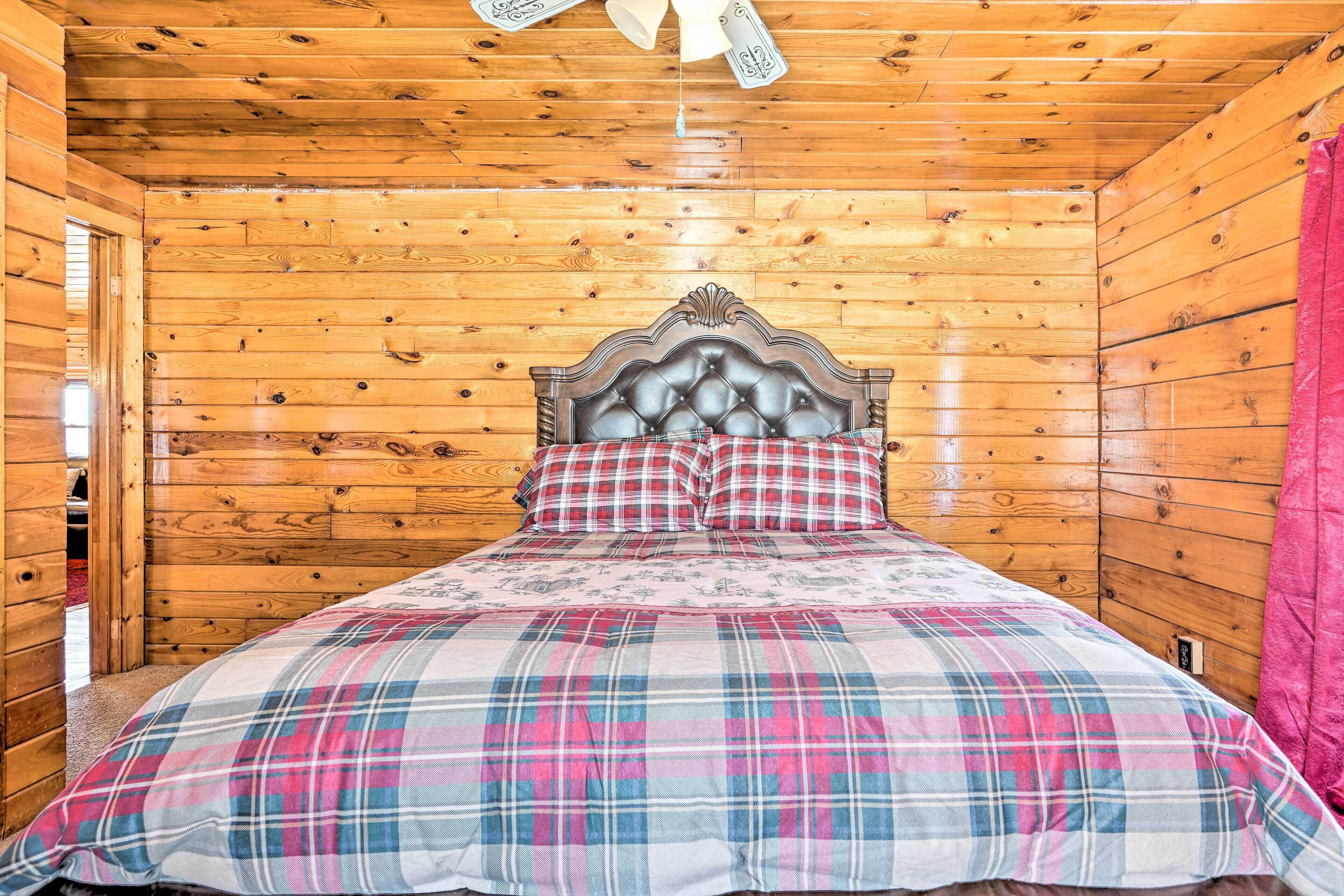 A wooden cabin bedroom with a bed, plaid bedding, and a wooden ceiling.