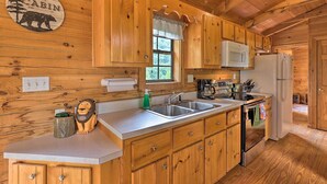 A cabin kitchen with wooden cabinets, a sink, a microwave, and a refrigerator. - Quaint Log Cabin w/ Views Near West Jefferson (Warrensville)