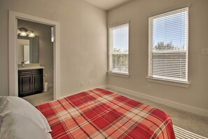 Enjoy a cozy retreat with a plaid bedspread, vanity, and two windows with blinds.