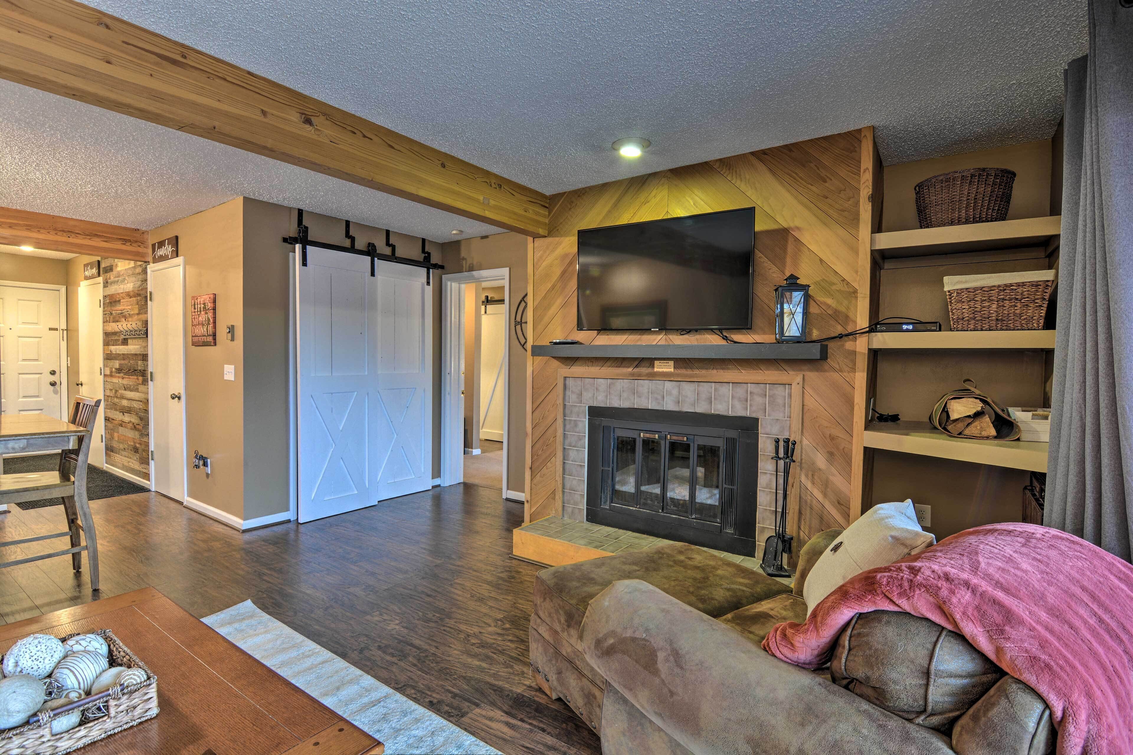 A cozy living room with a fireplace, a flat-screen TV, and a comfortable sofa.