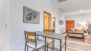 A dining area with a metal table and chairs, a wooden door, a sofa, and a lamp. - Modern Mtn Home w/ Sports Court, Near Alto Lake! (Alto)