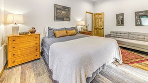 A bedroom with a bed, dresser, nightstand, and a sofa. - Modern Mtn Home w/ Sports Court, Near Alto Lake! (Alto)