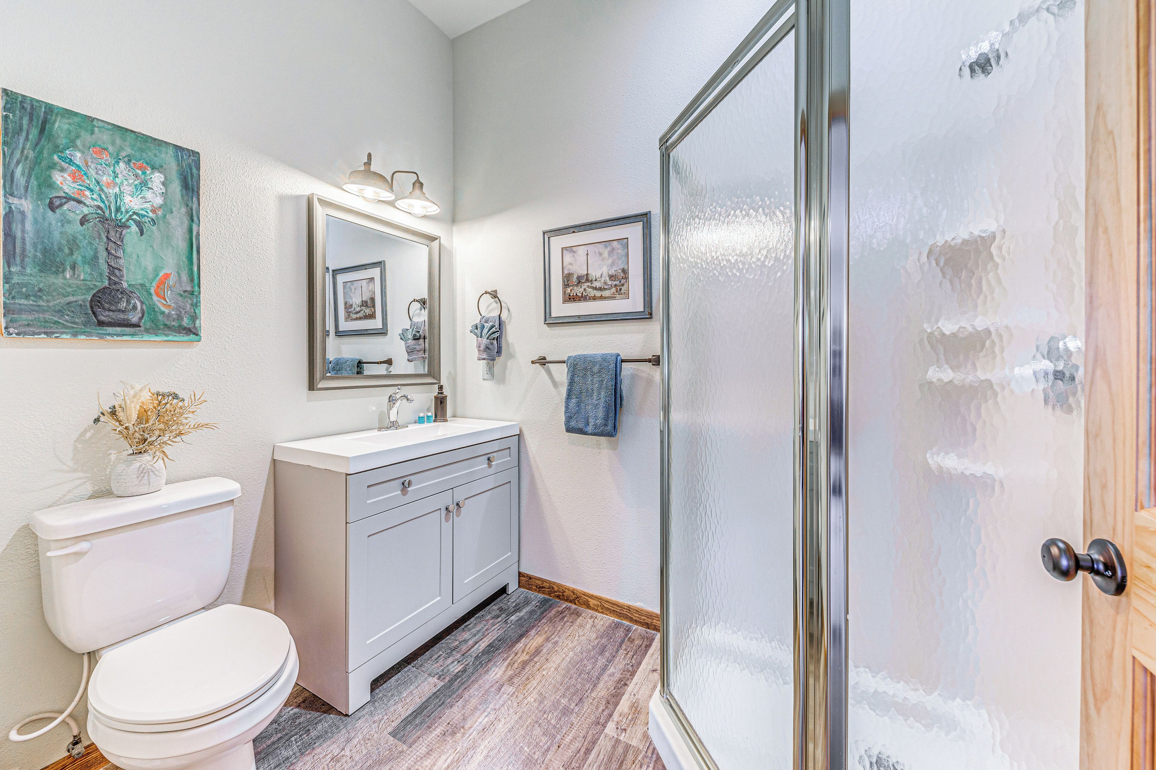 A bathroom with a toilet, sink, mirror, and shower.