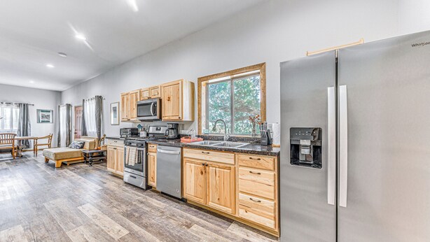A modern kitchen with wooden cabinets, stainless steel appliances, and a large window. - Modern Mtn Home w/ Sports Court, Near Alto Lake! (Alto)
