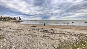 Una playa con piedras, un muelle de madera y un cielo nublado.