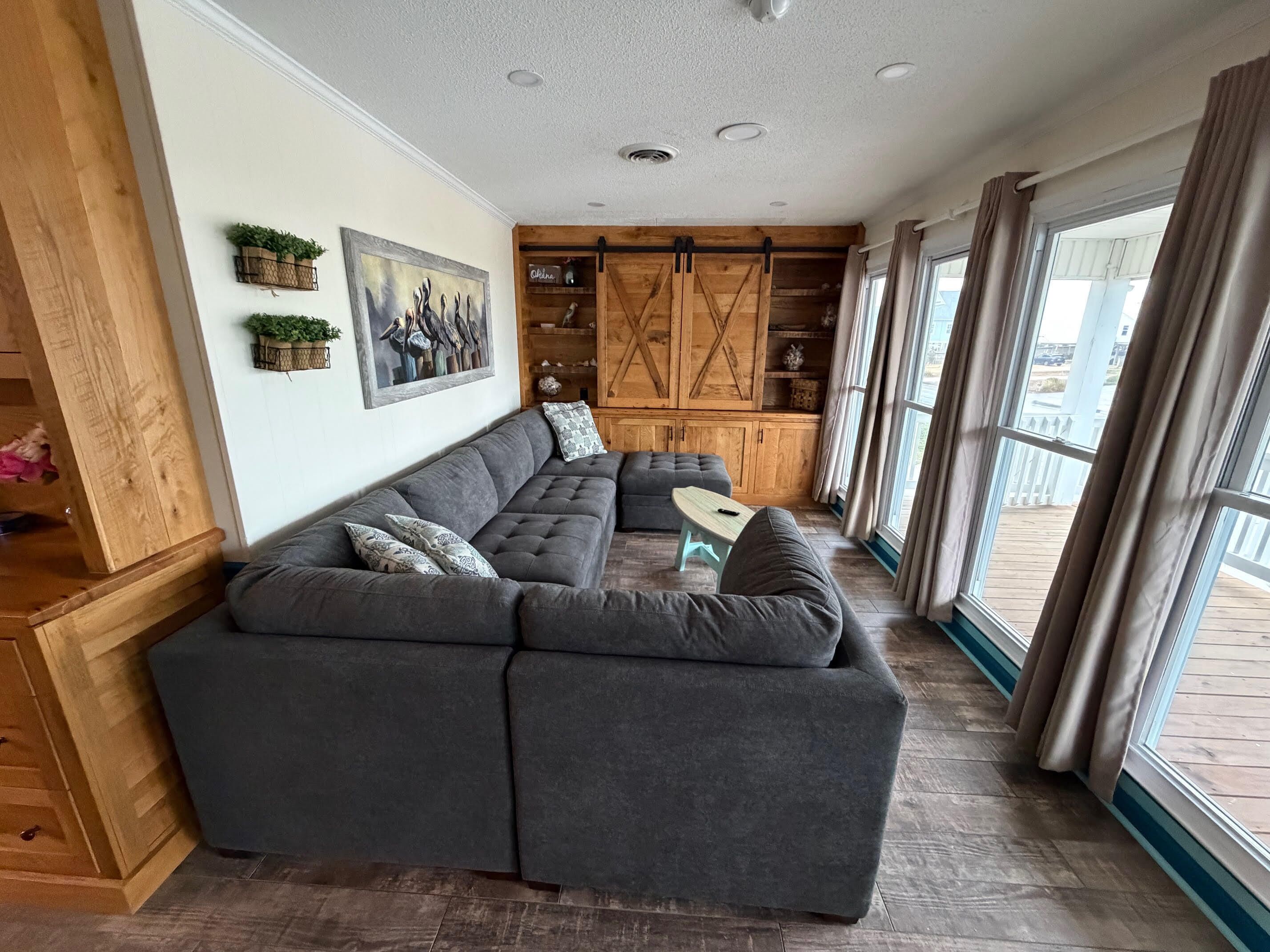 Una sala moderna con un sofá modular, una mesita y un ventanal con cortinas.