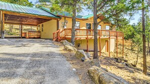 Eine Lodge mit überdachter Veranda, einer Holzterrasse und Blick auf den umliegenden Wald.