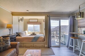 A bedroom with a bed, a desk, a chair, a sofa, and a view of the outdoors. - Studio ~ 3 Mi to Great Smoky Mountain Nat'l Park! (Gatlinburg)
