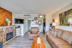 A living room with a fireplace, leather armchair, wooden coffee table, and a couch. - Studio ~ 3 Mi to Great Smoky Mountain Nat'l Park! (Gatlinburg)