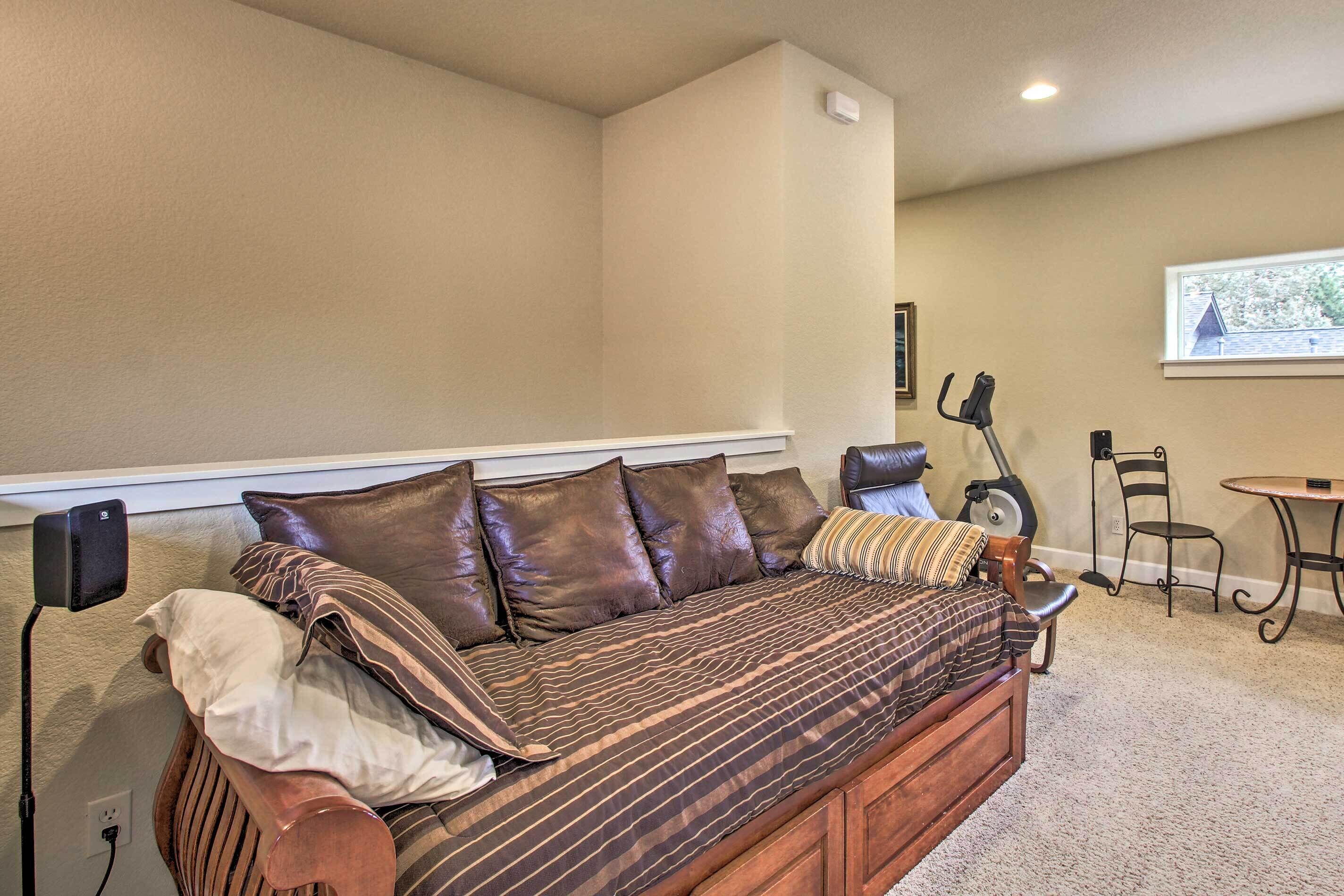 A cozy living room with a sofa, a treadmill, and a dining area.