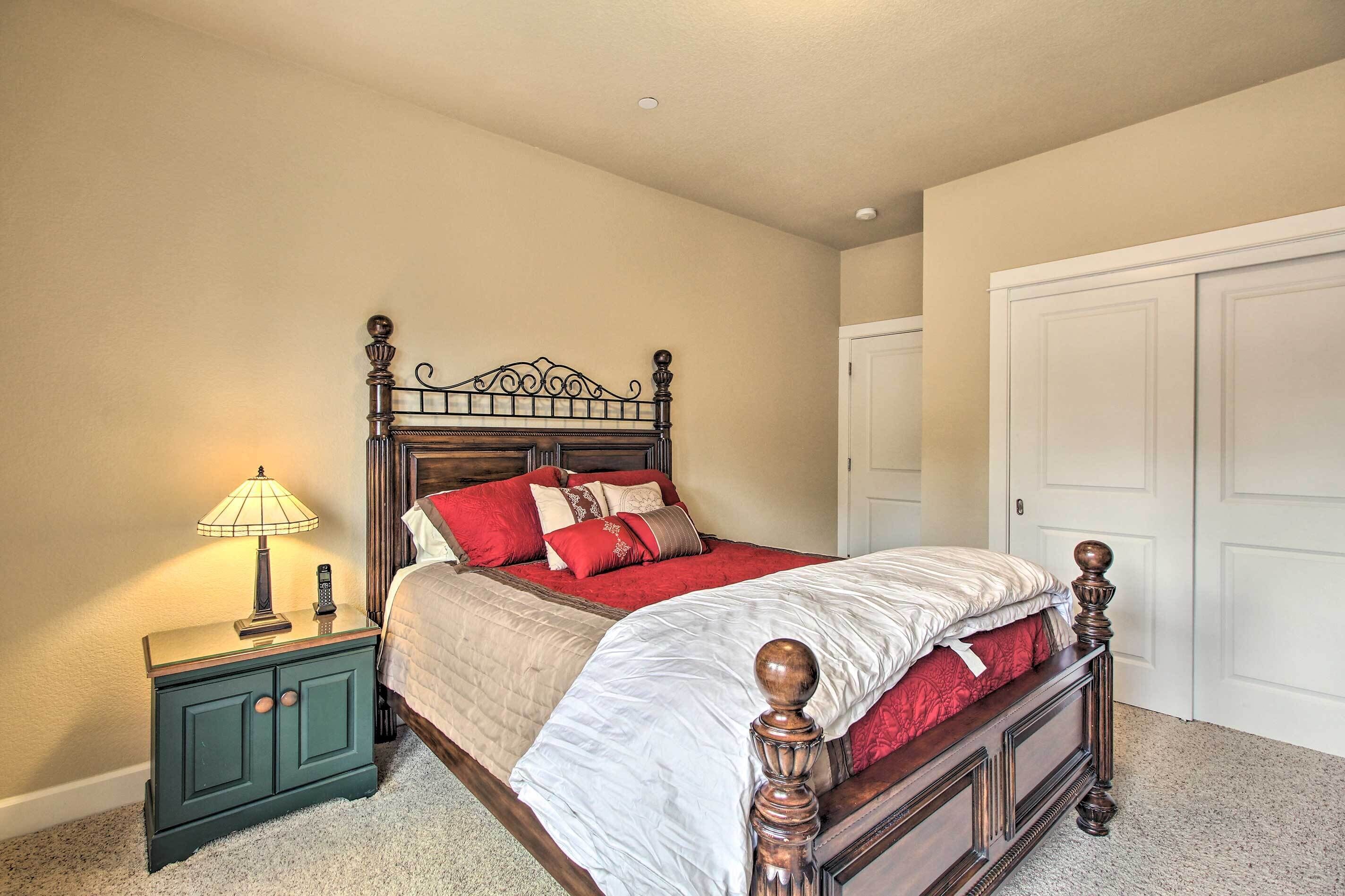 A bedroom with a wooden four-poster bed, a nightstand with a lamp, and a closet.