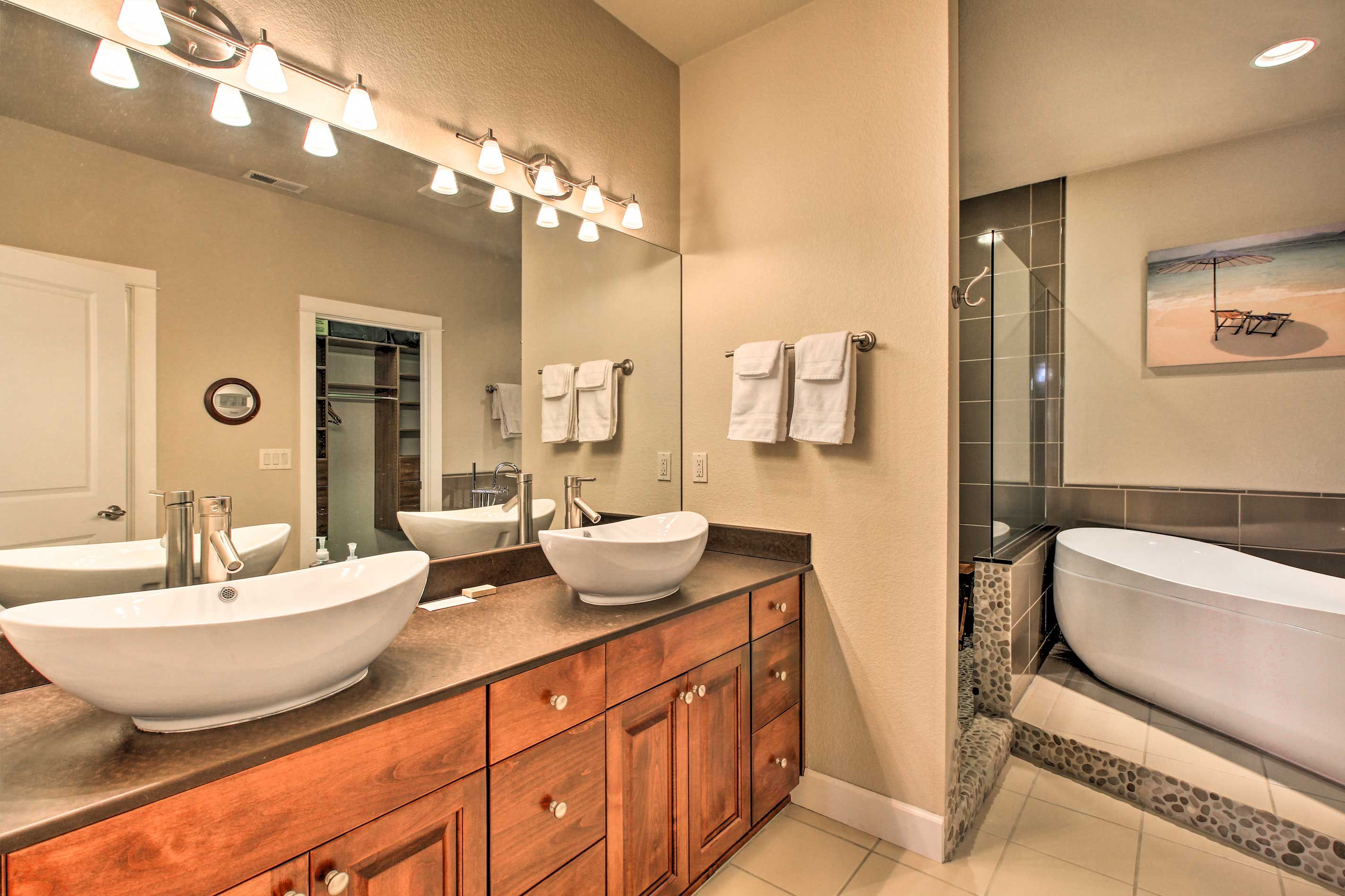 A bathroom with two sinks, a large mirror, and a bathtub.
