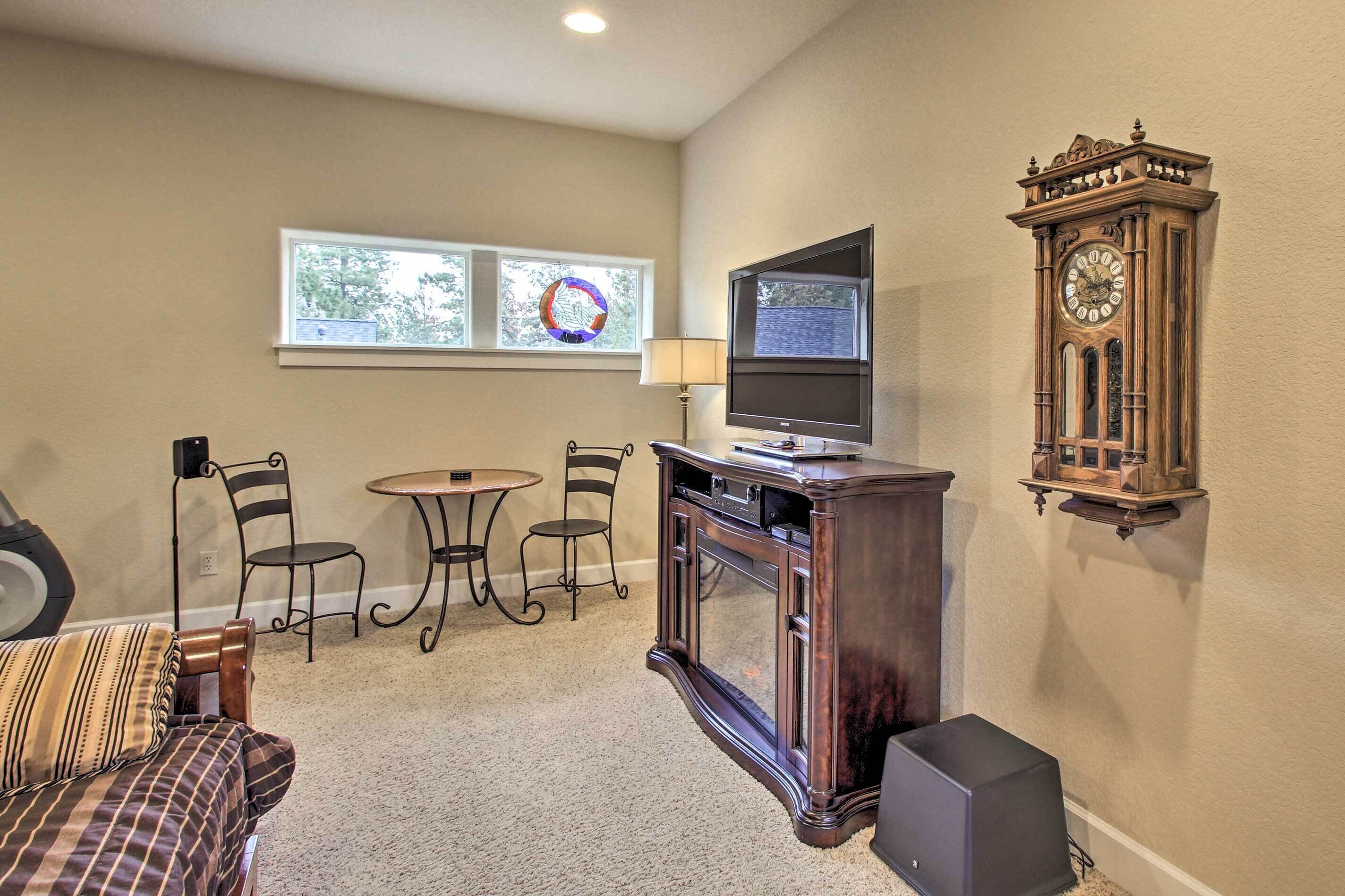 A living room with a sofa, a TV, a clock, and a fireplace.