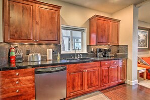 A kitchen with wooden cabinets, a dishwasher, a coffee maker, and a window.