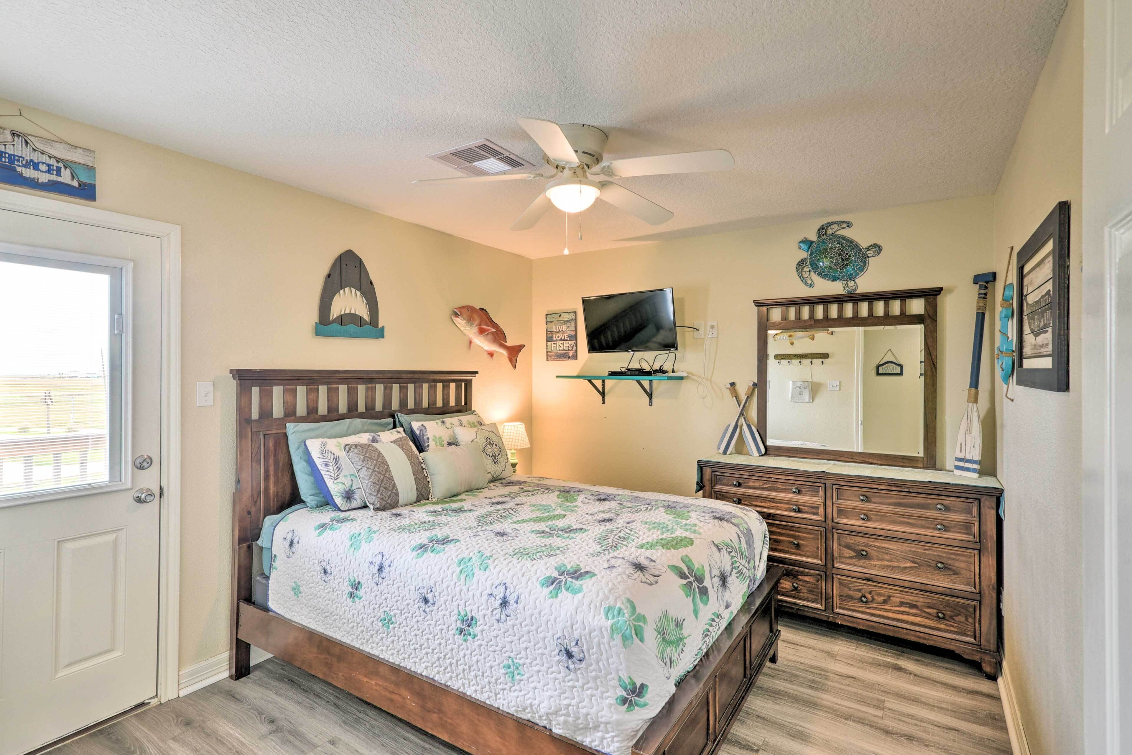 A bedroom with a wooden bed, a ceiling fan, a TV, and a dresser.