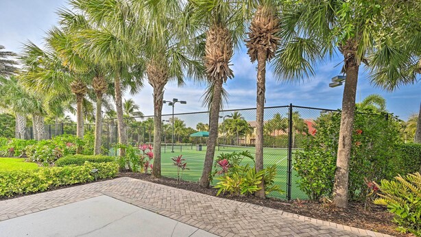 A paved walkway with palm trees and a tennis court in the background. - Alluring Naples Retreat w/ Resort Amenities! (Naples)
