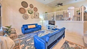 A living room with a blue sofa, a television, and decorative wall art. - Alluring Naples Retreat w/ Resort Amenities! (Naples)