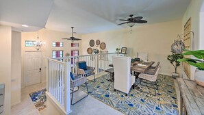A spacious living area with a high ceiling, ceiling fans, a dining table with chairs, a white railing, and a patterned rug. - Alluring Naples Retreat w/ Resort Amenities! (Naples)