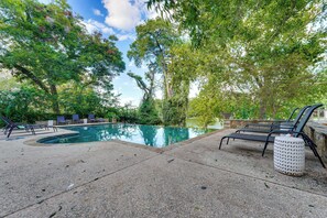 A swimming pool with lounge chairs and a stone wall.