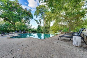 A swimming pool with lounge chairs and a stone wall.