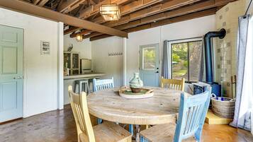 Un comedor rústico con una mesa y sillas de madera, una lámpara colgante y vistas por una ventana.