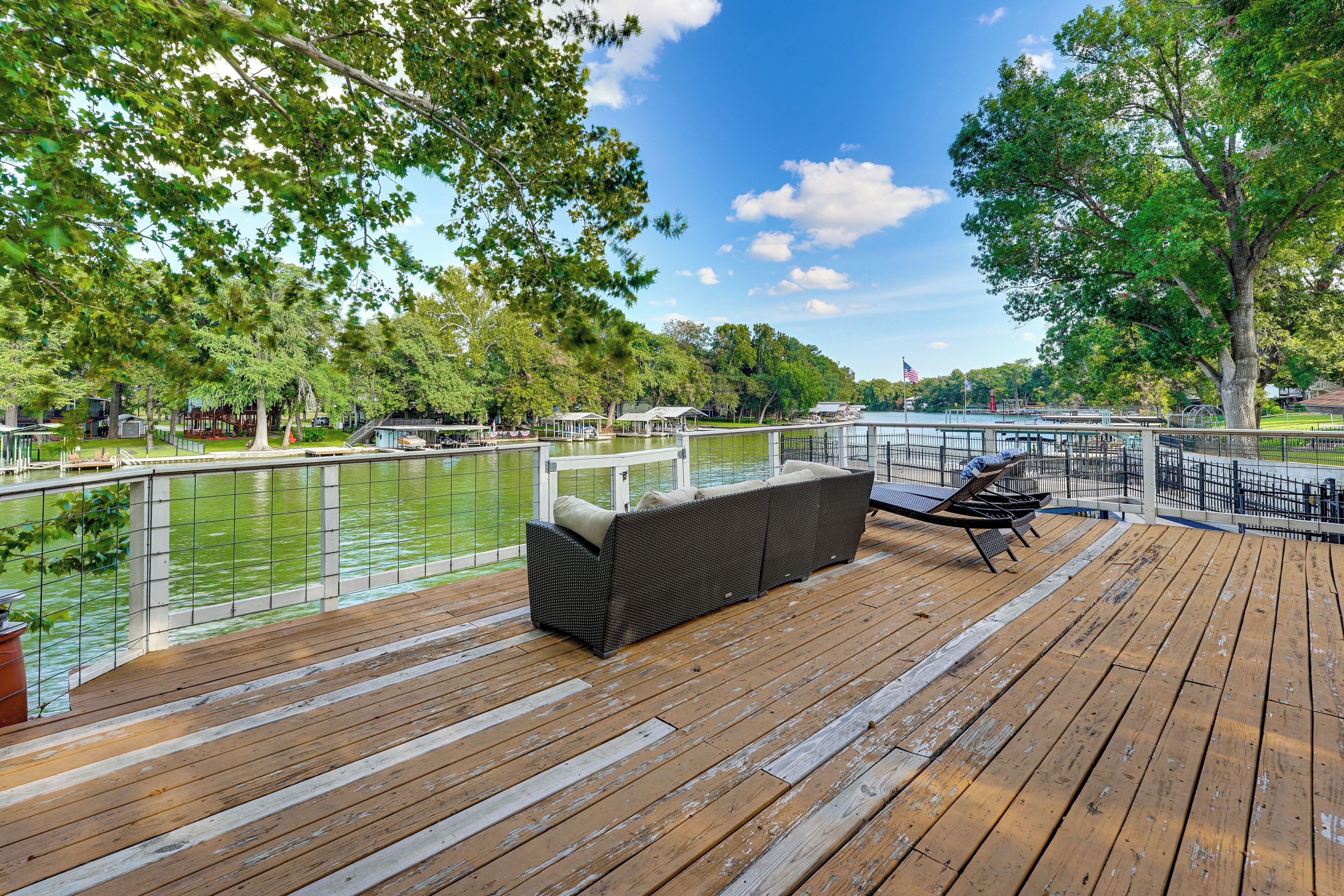 Une terrasse en bois avec des sièges extérieurs et une vue sur une rivière.