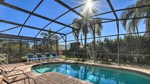 A pool area with a glass enclosure, blue lounge chairs, and a brick patio. - Villa w/ Game Room: 10 Mi to Disney! (Davenport)