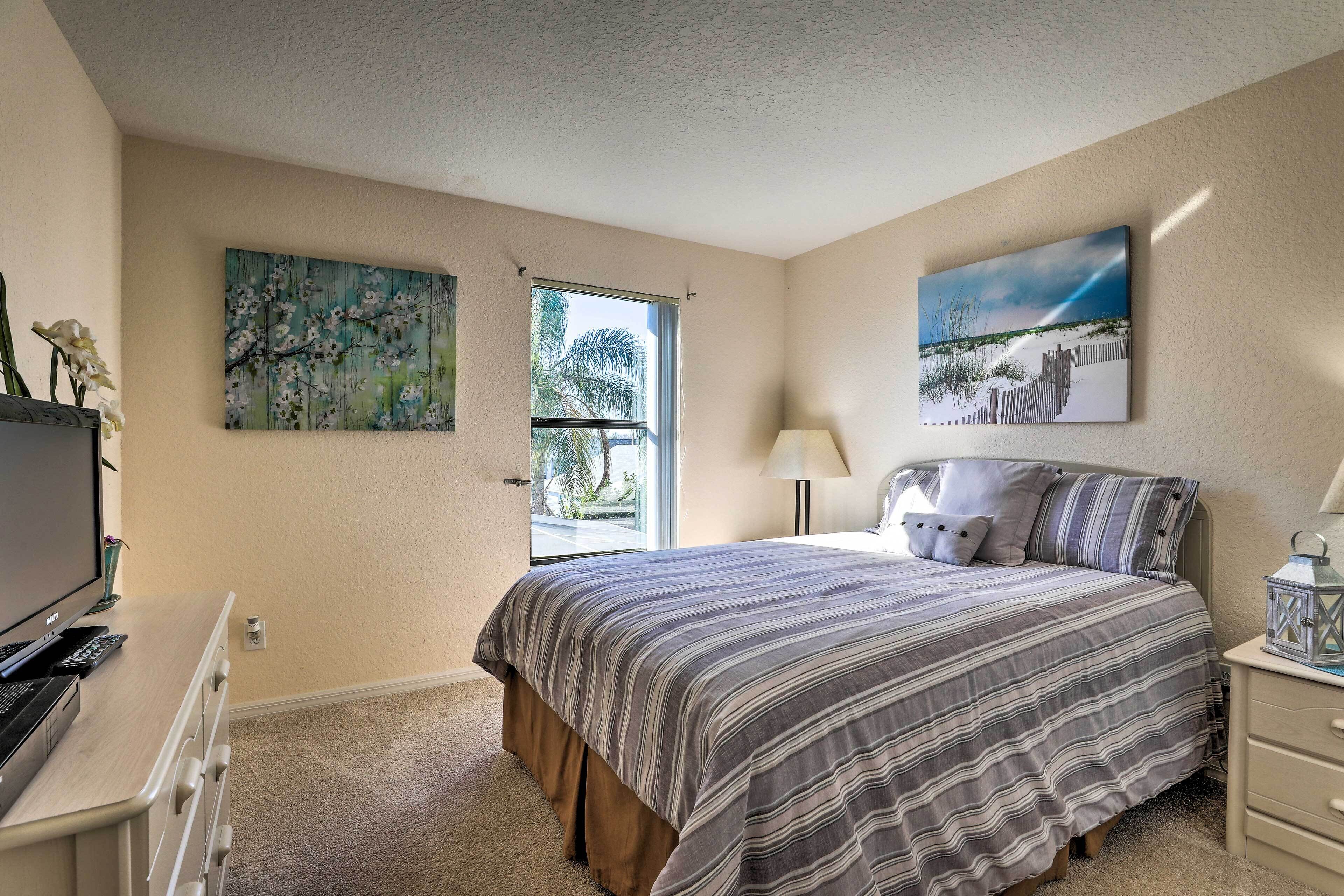 A bedroom with a bed, a desk with a computer, a lamp, and artwork on the walls.