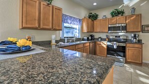A kitchen with granite countertops, wooden cabinets, a stainless steel microwave, and an oven. - Villa w/ Game Room: 10 Mi to Disney! (Davenport)