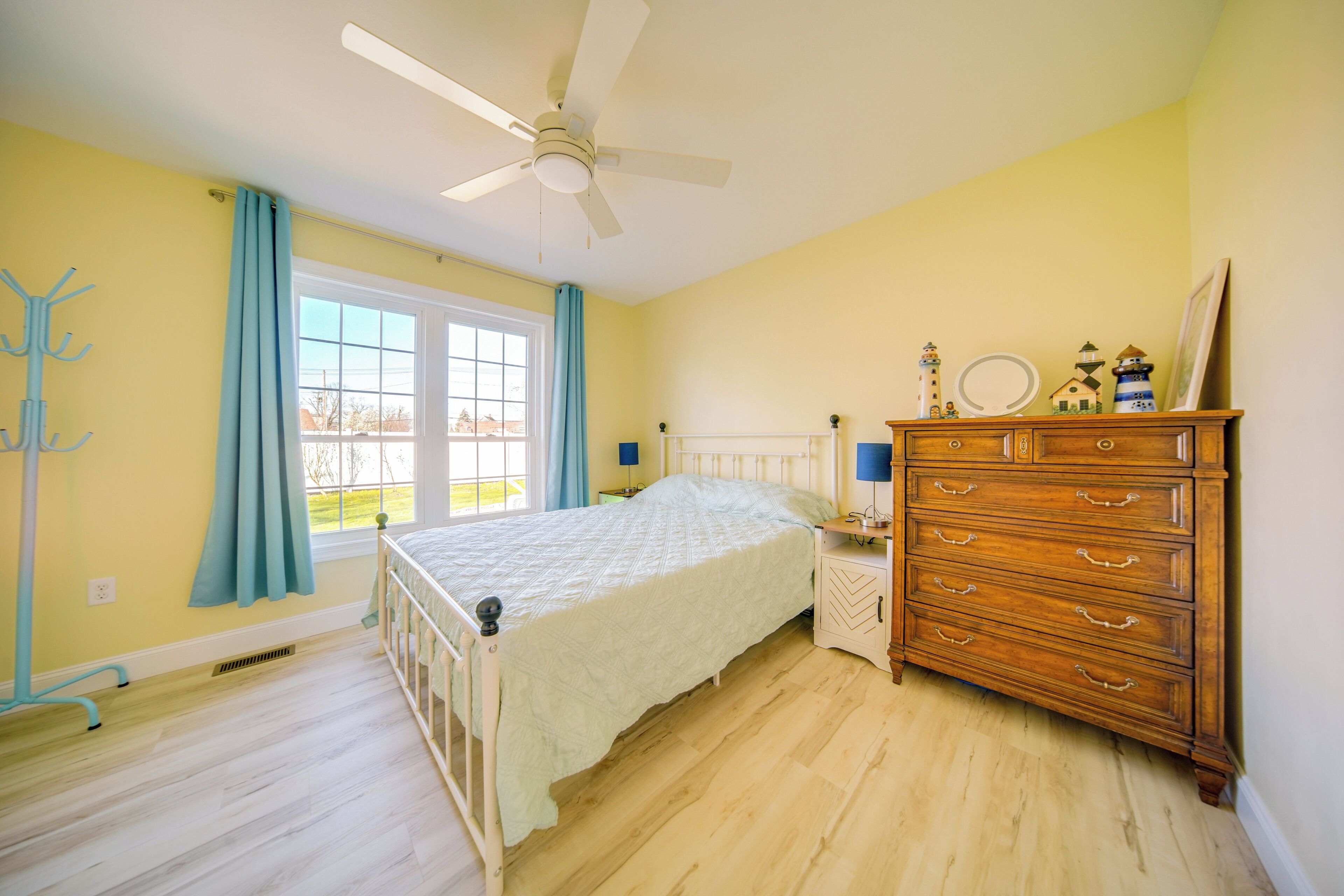 A bedroom with a bed, wooden dresser, and a ceiling fan.